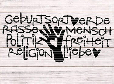Schwarze Plottgrafik mit den Worten 'Geburtsort Erde, Rasse Mensch, Politik Freiheit, Religion Liebe' und einer stilisierten Hand mit Herz auf hellem Holzuntergrund.
