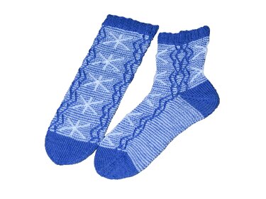 Blau gestricktes Sockenpaar mit Stern- und Wellenmuster auf weißem Hintergrund, eine Socke flach, die andere geformt.