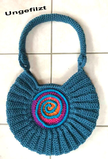 Ungefilzte blaue gehäkelte Henkeltasche mit mehrfarbiger Spirale auf hellem Fliesenboden