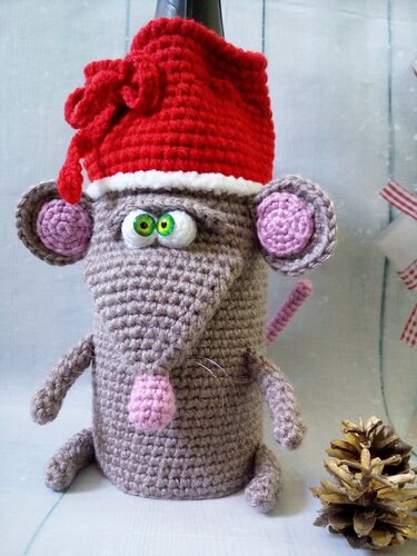 Whimsical gray amigurumi mouse with green eyes and a festive red hat