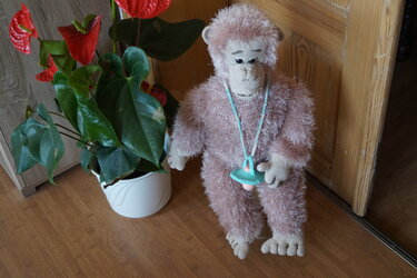 Großer Amigurumi-Affe aus rosabraunem Flauschgarn mit gehäkeltem Anhänger