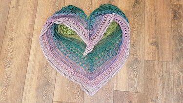 Dreieckstuch gehäkelt mit Ombré-Farben in Herzform auf Holzfußboden