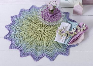 Sternförmiges gehäkeltes Deckchen mit Farbverlauf, Servietten und kleiner Vase