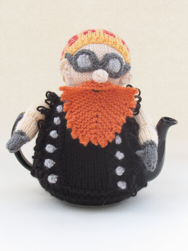 Knitted character tea cozy with orange beard and grey goggles on a teapot