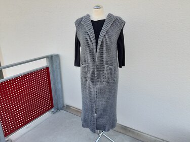 Gehäkelte lange ärmellose Weste mit Kapuze und Taschen in Grau auf Schneiderbüste
