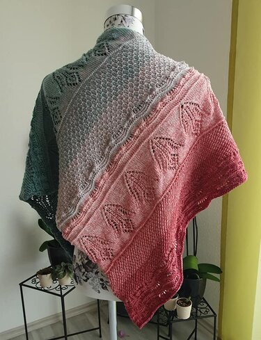 Rückansicht eines gestrickten Dreieckstuchs mit Farbverlauf von Grün zu Rot und sichtbaren Loch- und Strukturmustern.