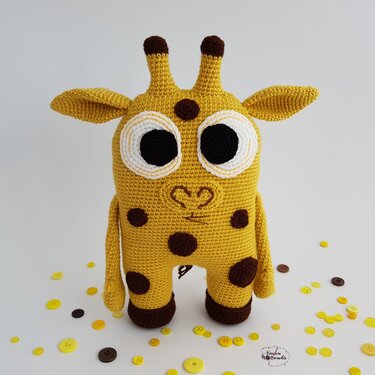 Niedliche gelbe Amigurumi‑Giraffe mit großen Augen und braunen Flecken
