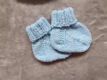 Hellblaue Babysöckchen mit umgeschlagenem Bündchen liegend
