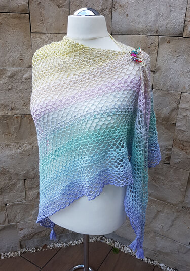 Gehäkeltes Dreieckstuch in Pastelltönen mit Spitzenmuster, Quasten und Schmucknadel auf Mannequin
