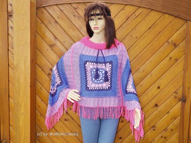 Mannequin trägt gehäkelten Poncho mit großen Granny
Squares, geripptem Kragen, Kordel und pinken Fransen