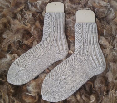 Beige gestrickte Damensocken mit Zopfmuster auf Sockenformern auf Wollfleece