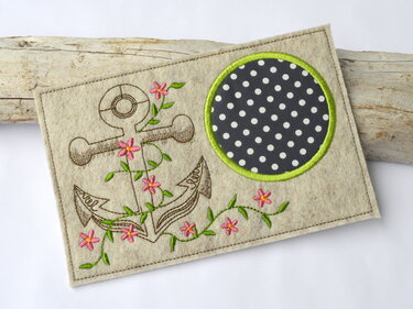 Maritimer Tassenteppich aus Filz mit besticktem Anker, grüner Ranken- und pinken Blütenverzierung sowie gepunkteter Tassenfläche