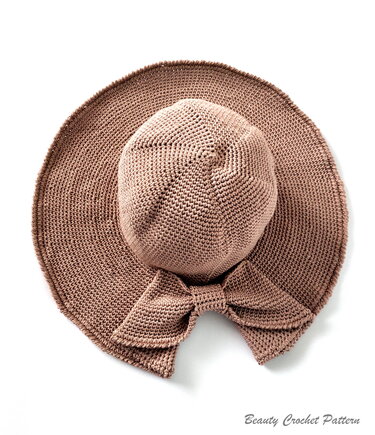Light brown crocheted wide-brim sun hat with a matching bow seen from above on a white background.