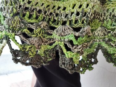 Gestrickter Ponchoausschnitt in melierten Grüntönen mit offenem Lochmuster und dekorativer Wellenkante