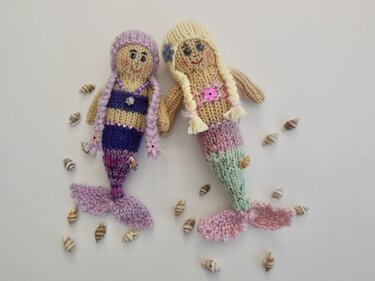 Zwei gestrickte Amigurumi-Meerjungfrauen mit Zöpfen, Perlen und Muscheln