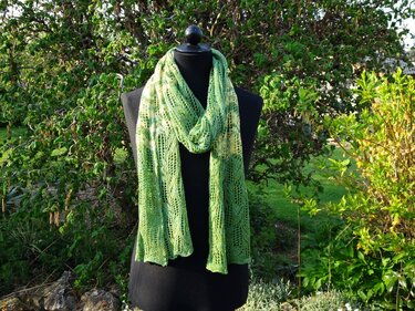 Langer schmaler Lochstrick-Schal in verschiedenen Grüntönen auf Schneiderpuppe im Garten