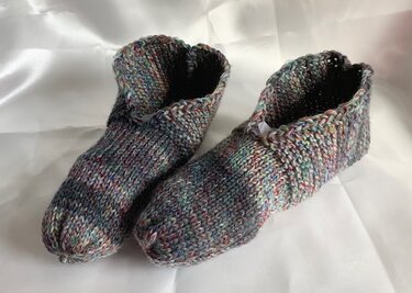 Zwei unisex gestrickte Pantoffeln in mehrfarbiger Melange, Vorder- und Seitenansicht