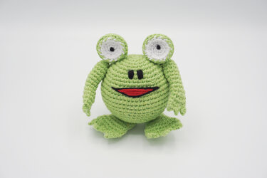 Gehäkelter hellgrüner Amigurumi-Frosch mit weißen Augen und rotem Mund
