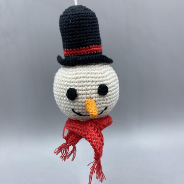 Gehäkelter Schneemannkopf mit schwarzem Zylinder und rotem Schal, hängend