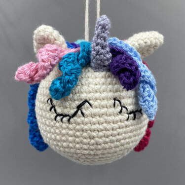 Kleine gehäkelte Einhorn-Anhänger-Kugel mit Aufhängeschlaufe und mehrfarbiger Mähne
