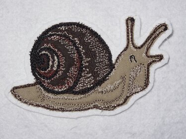 Gestickte Schnecke mit braunem Spiralschneckenhaus auf wei
ßem Stoff