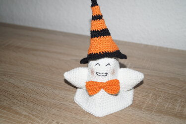 Kleines weißes Häkelgespenst mit gestreiftem orange-schwarzem Hut und oranger Schleife