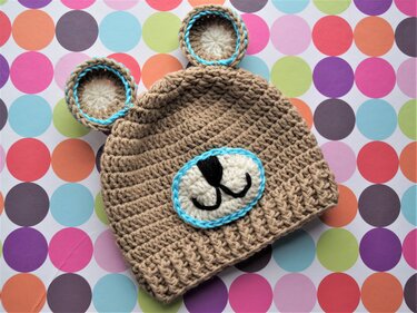 Beige gehäkelte Babymütze mit Bärenohren und türkiser Umrandung