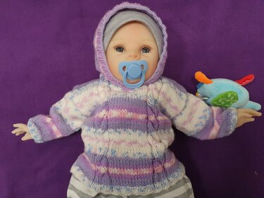 Detailansicht gestrickter Babypullover mit Kapuze, pastellstreifen und Zopfmotiv