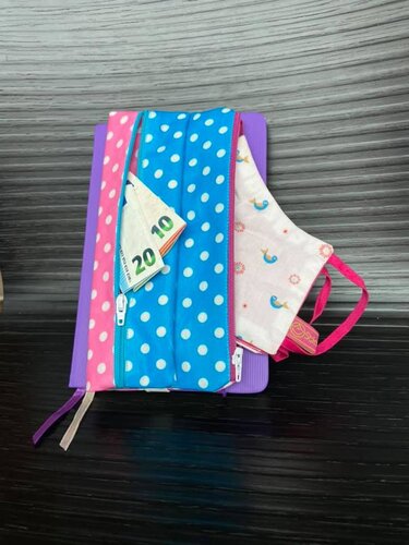 Genähte Geldbörse mit zwei Reißverschlüssen aus blau-weißen und rosa-weißen Punkten, gefaltete Geldscheine und kleine Stofftasche