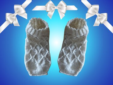 Weiße Stricksocken mit Rautenmuster auf blauem Hintergrund mit weißen Schleifen