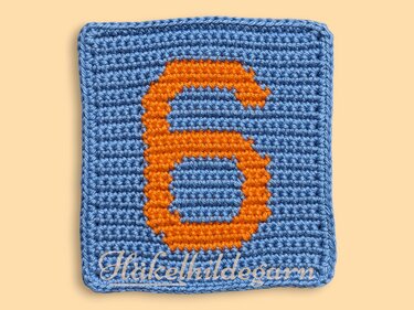 Gehäkeltes Pixelquadrat mit orangefarbener Zahl 6