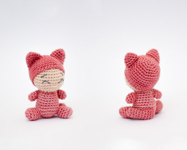 Zwei rosa gehäkelte Amigurumi-Katzen, eine von vorne mit lächelnder Miene, die andere von hinten.