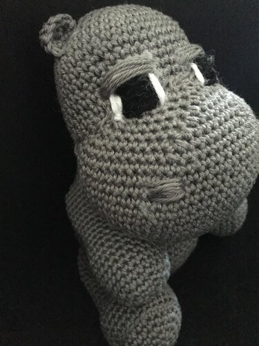 Gray crocheted hippo amigurumi with white teeth on black background