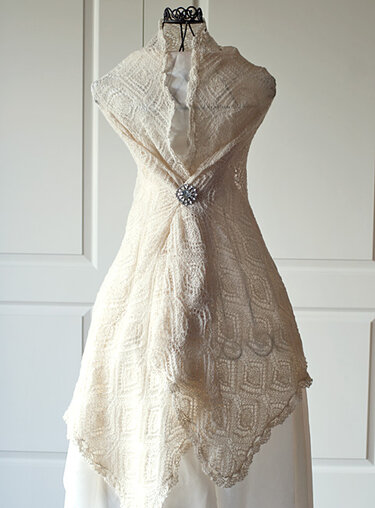 Elfenbeinfarbenes gestricktes Lacetuch mit Rautenmuster, auf Büste drapiert und mit Brosche befestigt