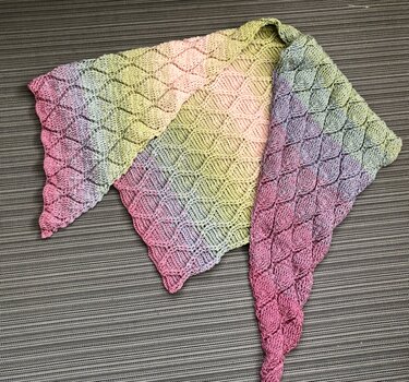 Gehäkeltes Dreieckstuch mit diamantförmigem Relief und rosa‑grünem Farbverlauf auf neutralem Untergrund