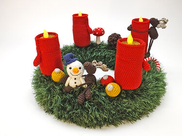 Gehäkelter grüner Adventskranz mit vier roten Kerzen und kleinem Schneemann