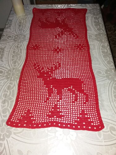 Roter, gehäkelter Tischläufer mit Hirschmotiven auf hellem Tischtuch