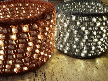 Zwei grob gehäkelte Körbe in Terrakotta und Grau mit eingearbeiteten warmweißen Lichterketten