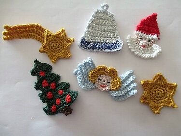Sechs kleine gehäkelte Weihnachts-Applikationen auf hellem Hintergrund: Komet, Stern, Glocke, Weihnachtsmann, Engel und Tannenbaum.