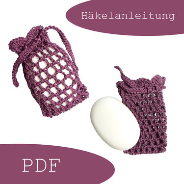 Zwei violette gehäkelte Netz-Seifensäckchen mit Zugband, eines enthält weiße Seife