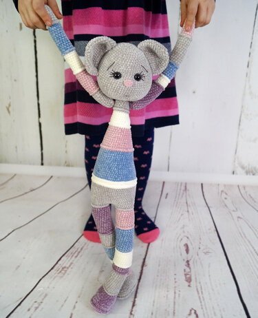 Gehäkelte Amigurumi‑Maus mit Pastellstreifen, von einem Kind an den Händen gehalten