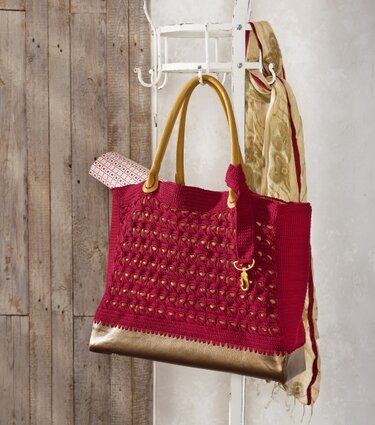 Rote gehäkelte Shopper-Tasche mit goldfarbenen Henkeln und Boden an Garderobenständer