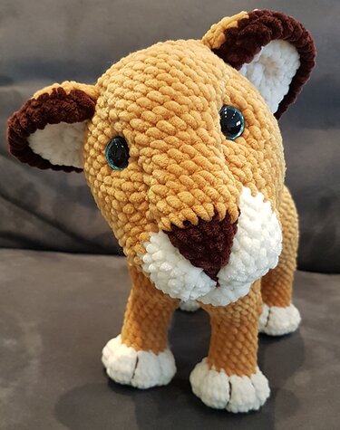 Gehäkeltes Löwenjunges Amigurumi in Hellbraun mit weißen Pfoten und dunkelbraunen Ohren, stehende Ansicht