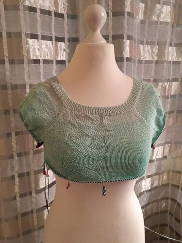 Unvollendeter mintgrüner Damenpullover auf Puppe mit Zopfmuster und Maschenmarkierern am Saum