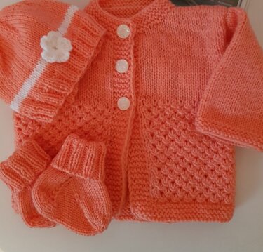 Dreiteiliges Babystrickset in Lachsrosa: Jäckchen, Mütze mit Blütenapplikation und Schühchen