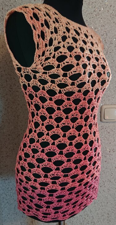 Lachsrosa-pinke gehäkelte Tunika mit offenem Lochmuster auf schwarzer Schaufensterpuppe