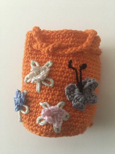 Kleines orangenes gehäkeltes Beutelchen mit Kordelzug, verziert mit Blumen und Schmetterling