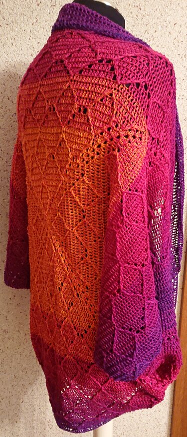 Gehäkelter Seelenwärmer in Orange‑Pink‑Lila mit Ajourrauten auf Schaufensterpuppe