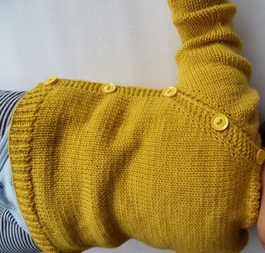 Senfgelbe gestrickte Babyjacke mit gelben Knöpfen