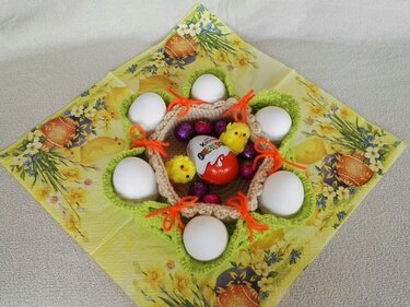 Gehäkeltes Blumen-Eierkörbchen mit weißen Eiern, Deko-Küken und Schokoei